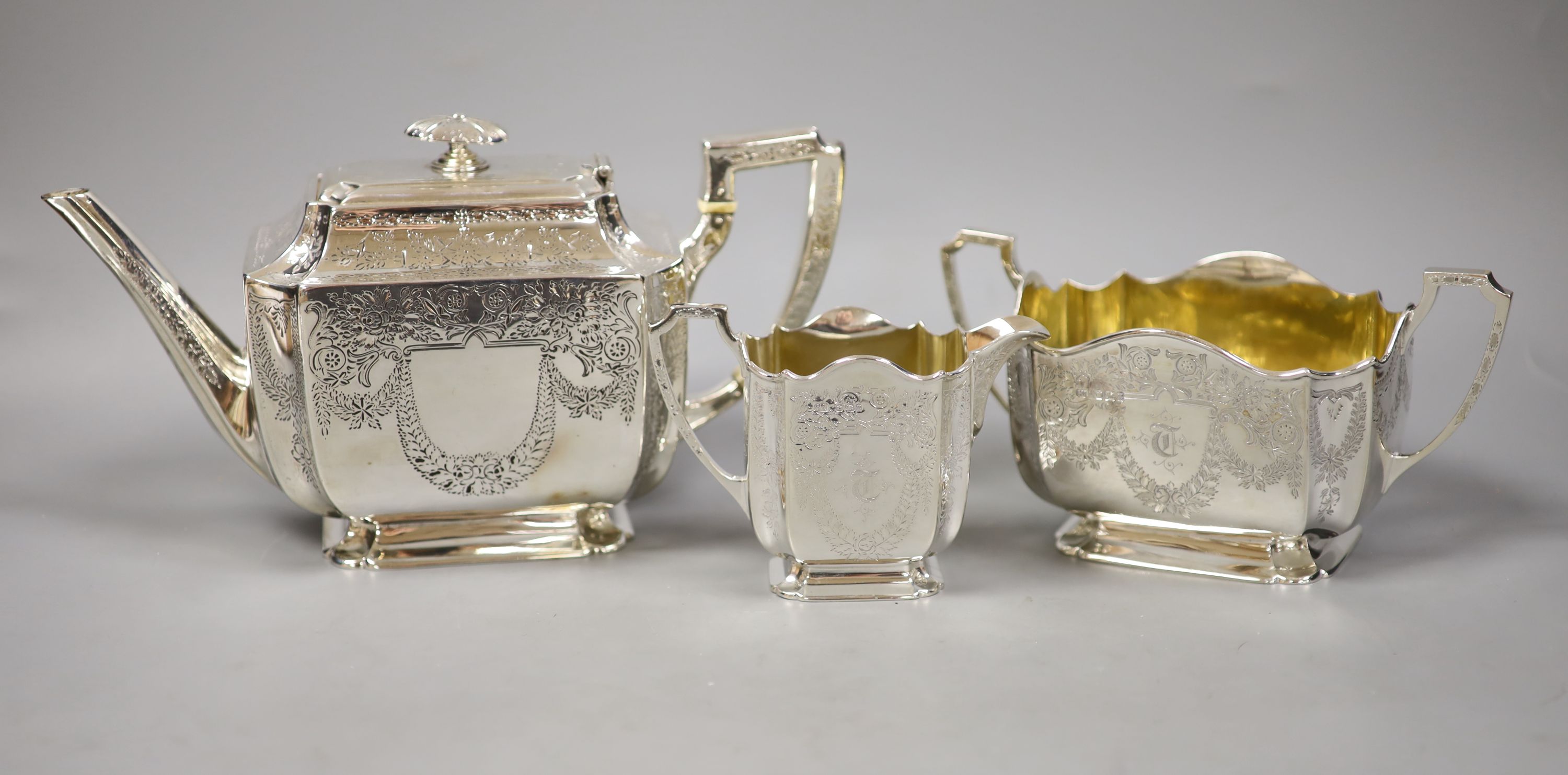 A silver three piece set, comprising teapot, twin-handled sugar basin and milk jug, with all-over chased decoration, London, 1893, by Atkins Brothers
